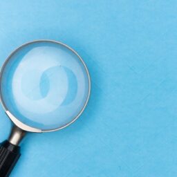 یک ذرهبین روی میز آبی برای نشان دادن قابلیت بزرگنمایی تصویر در وردپرس، با کلیک